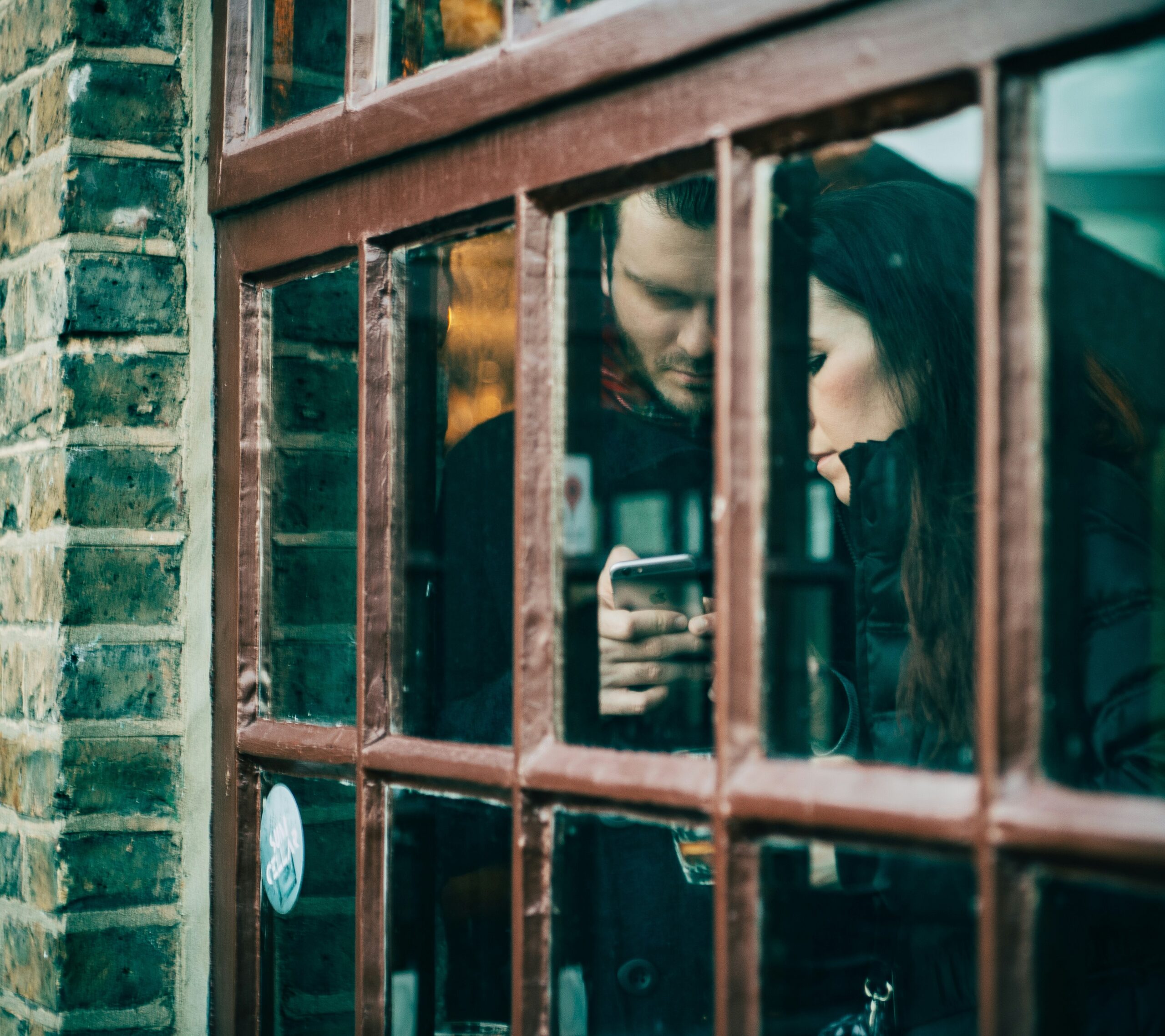 A person enjoying a steaming cup of coffee while checking their smartphone displaying a brewing schedule app.