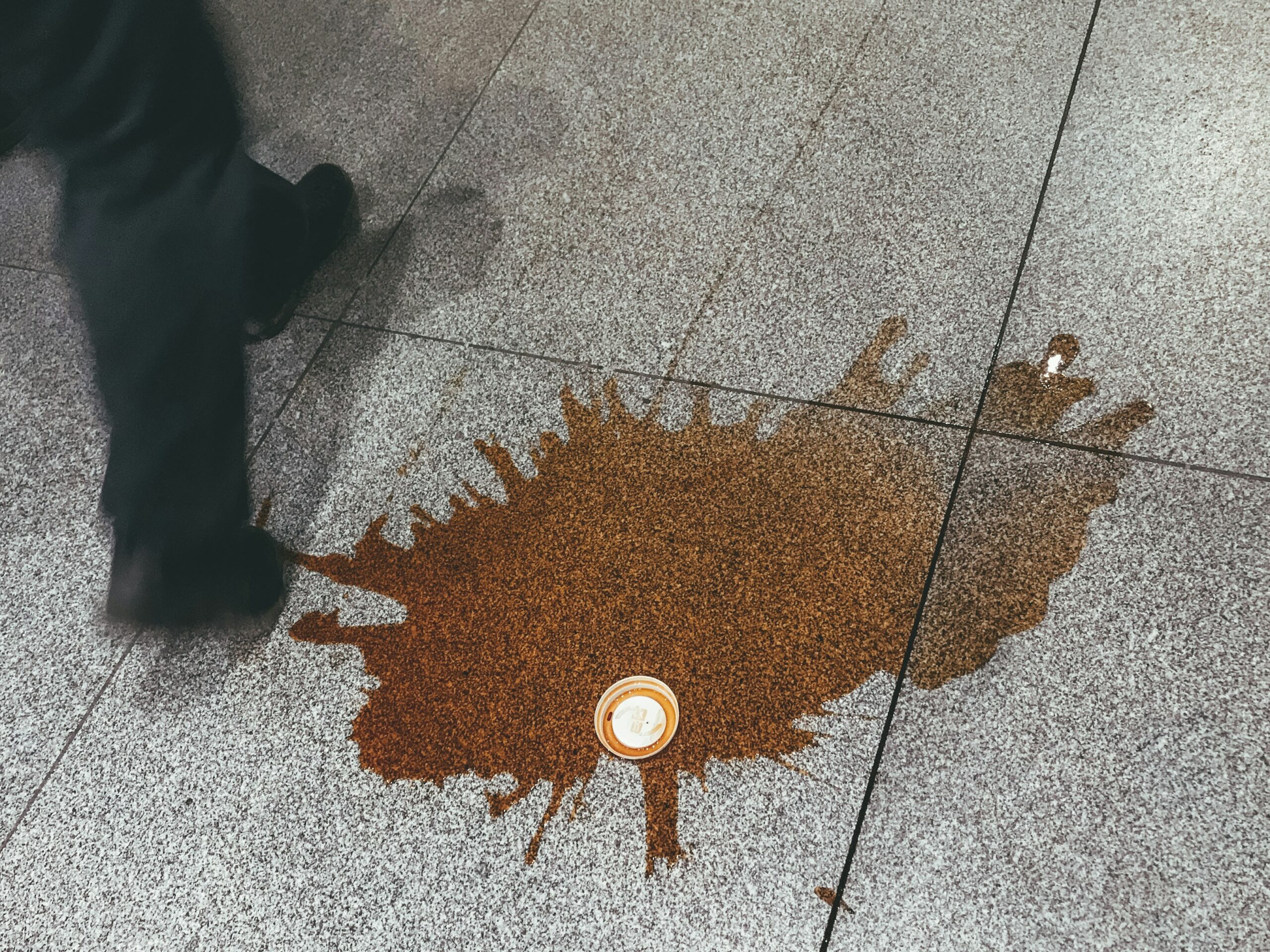 A spilled mug of poorly brewed coffee next to a smart coffee machine