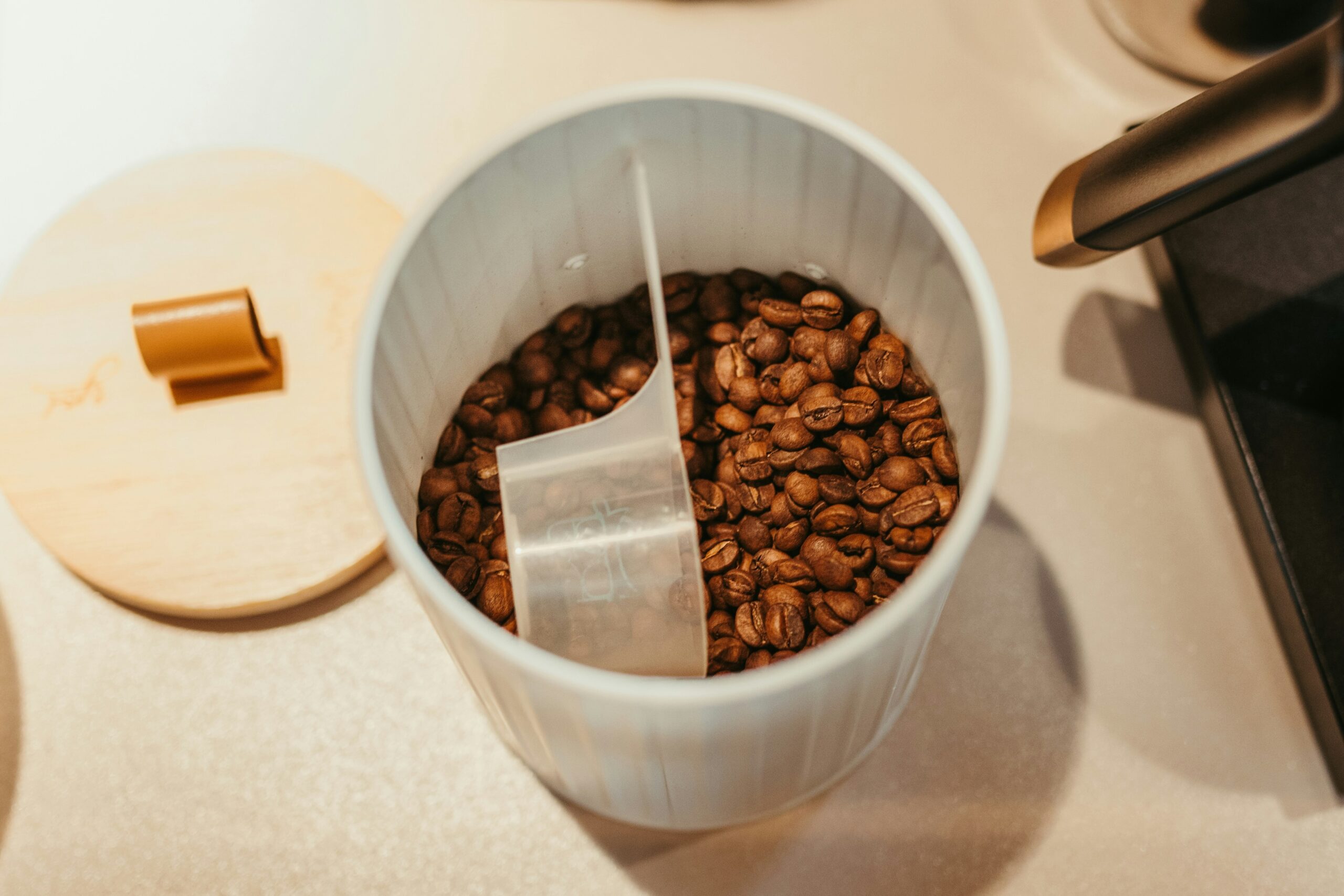 Clean coffee pot shining next to spilled coffee beans