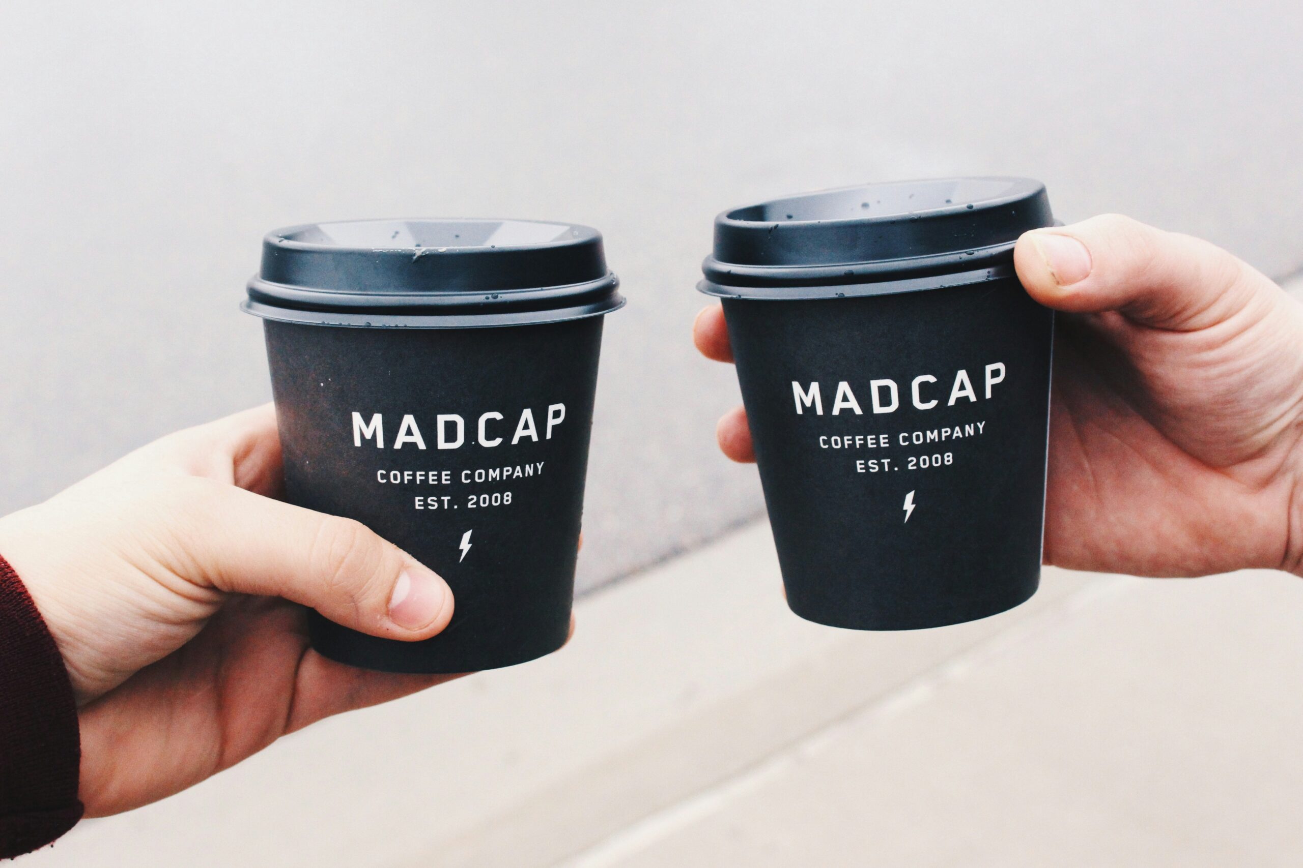 Two happy individuals holding cups of coffee made by smart coffee makers