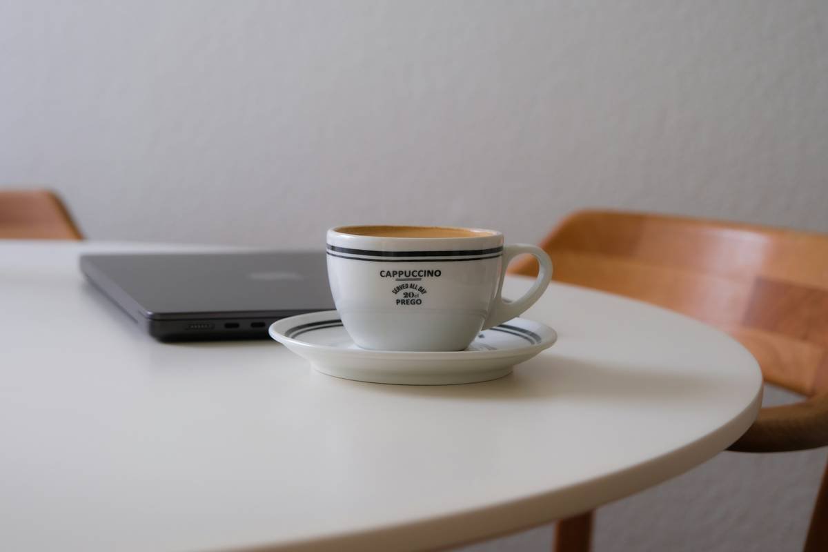 A woman smiling while holding a mug of coffee next to her smart coffee maker