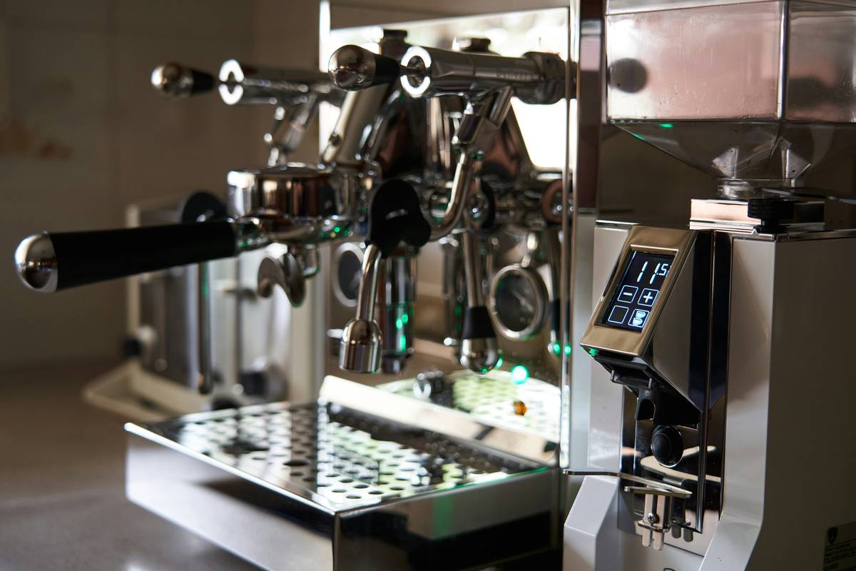 Sarah holding her smart coffee maker while smiling next to a steaming mug of freshly brewed coffee