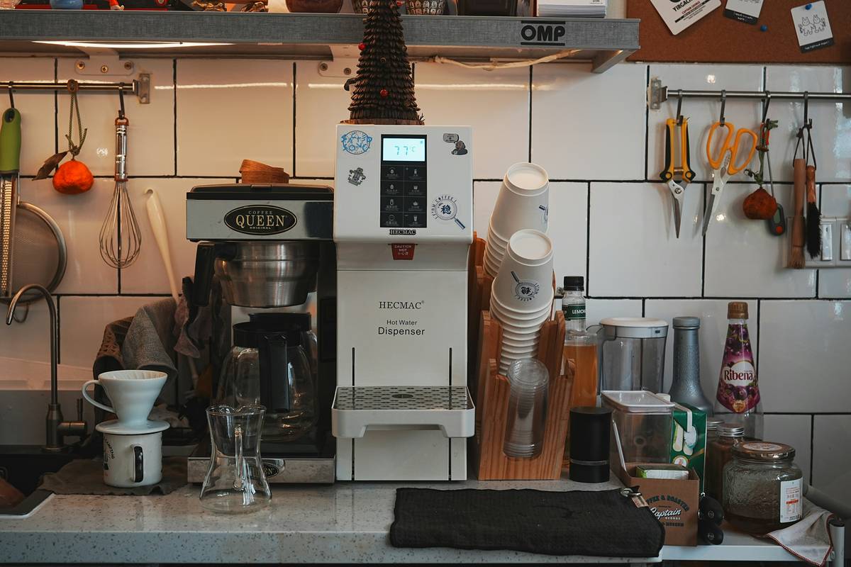 Smiling guest holding a mug next to a smart coffee maker.