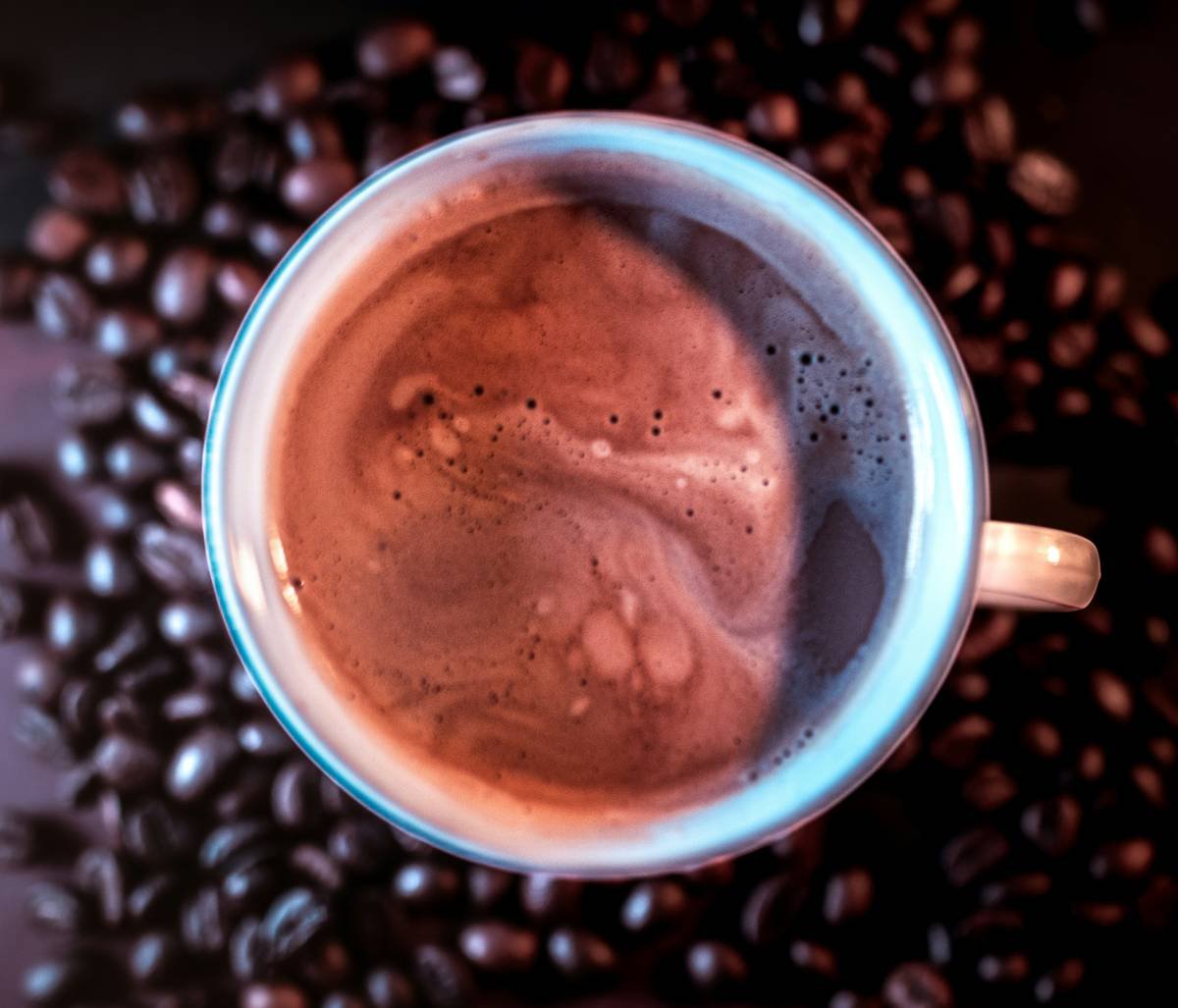A cup of coffee with roasted beans