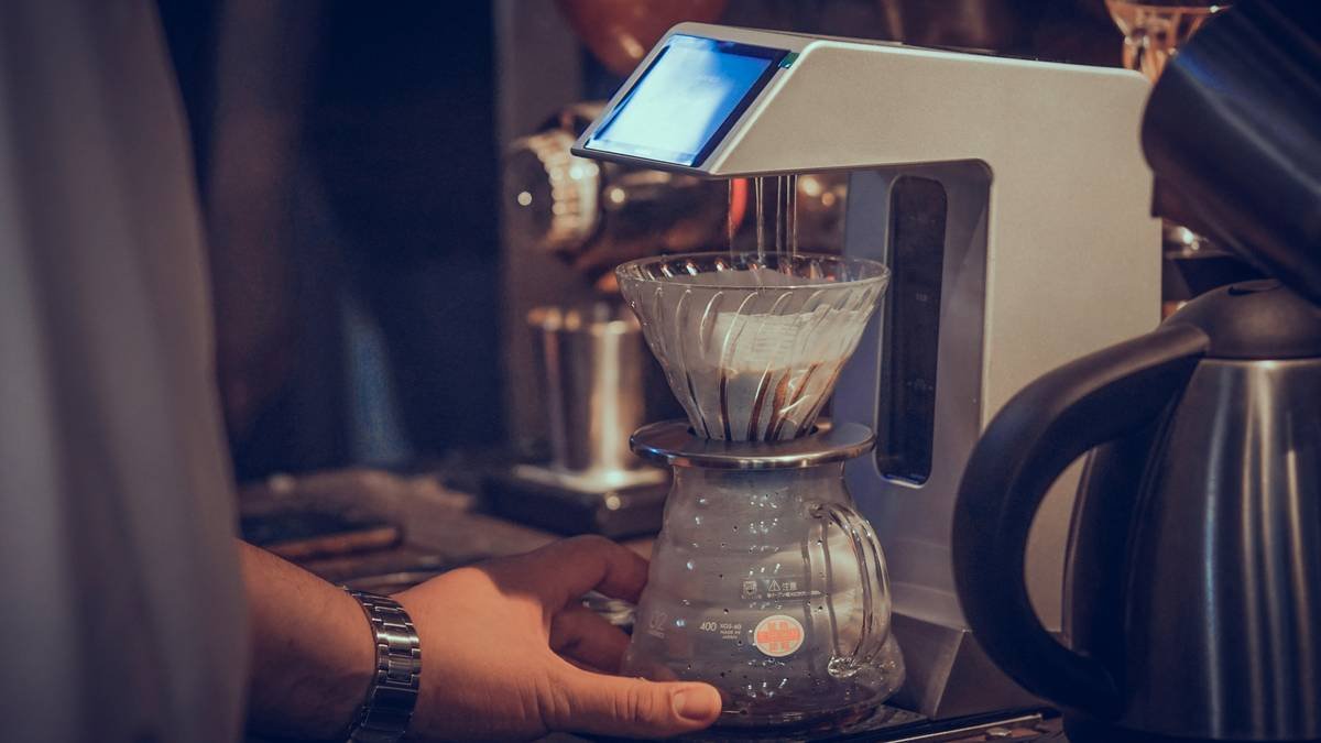 a person using a coffee maker to make a cup of coffee