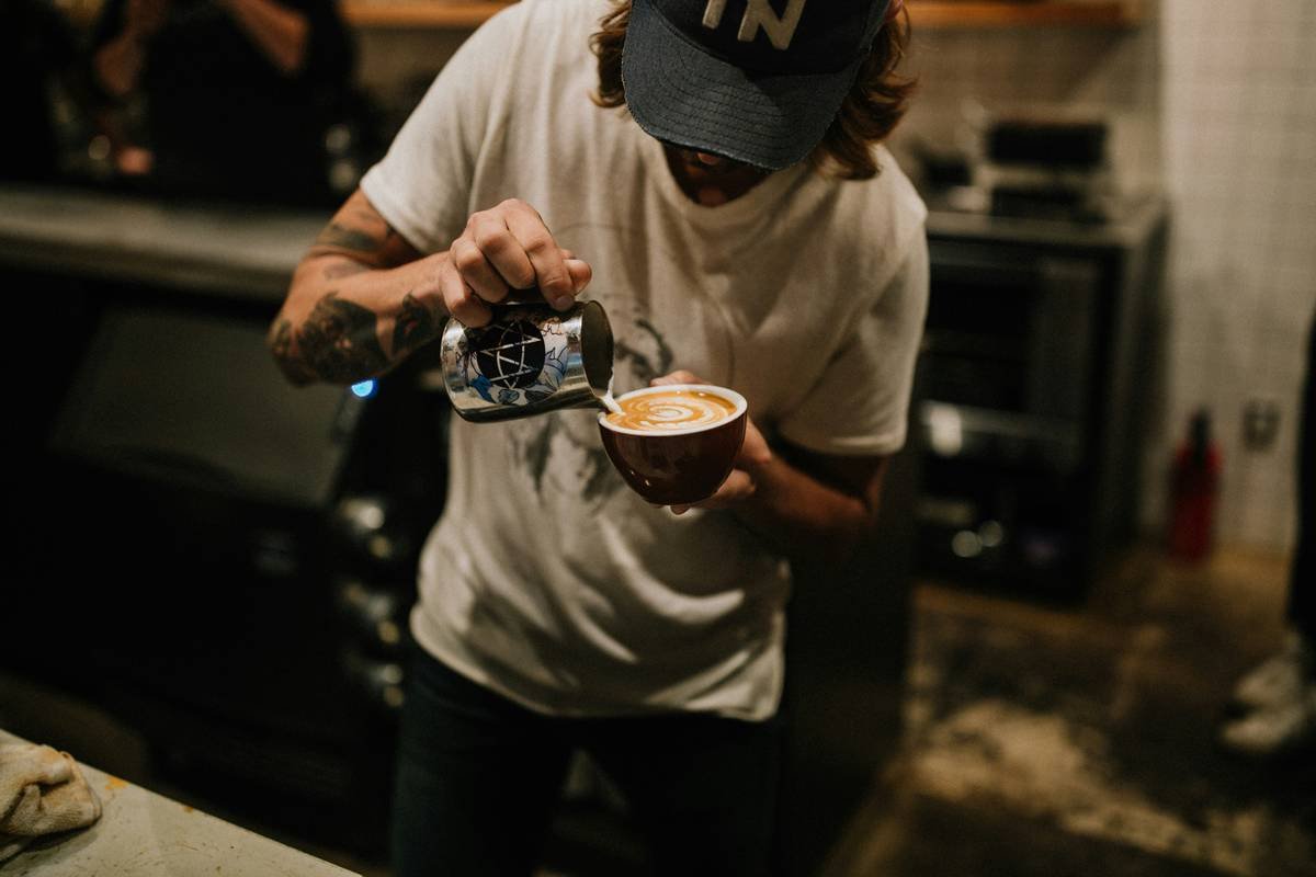 review of coffee makers showing a modern smart coffee maker on a kitchen counter with smartphone displaying brewing status